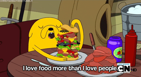Cartoon gif. Jake the Dog from Adventure Time is hugging a huge burger and his eyes are closed in ecstasy. He says, "I love food more than I love people."