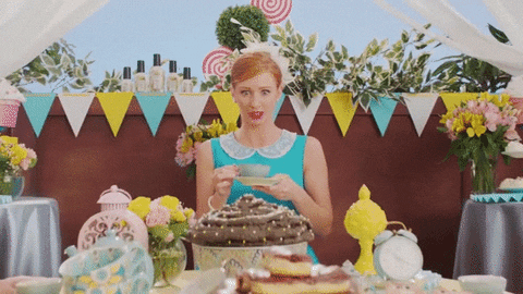 Ad gif. Woman in a blue dress holds a tea cup and saucer at an elaborate party in an advertisement for Poo Pourri. She looks down awkwardly then at us as we zoom in on her as she says “Oops.”