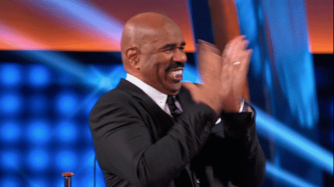 Reality TV gif. Steve Harvey on Celebrity Family Feud is incredibly eager and he has his shoulder hiked up to his ears as he claps his hands in front of his face with his quintessential wide, white-toothed smile.