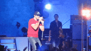 Celebrity gif. Luke Bryan is singing onstage at his concert and he suddenly hits a deep body roll, feeling himself.