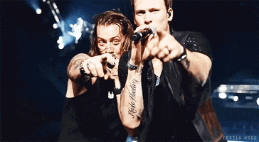 Music video gif. Tyler Hubbard and Brian Kelley of Florida Georgia Line point at us as they sing into their microphones on a brightly lit stage.