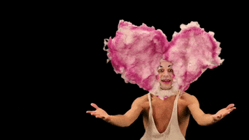 Video gif. A man in mime makeup with a pink cotton heart surrounding his face winks at us and gives two thumbs up. Text, "Nice."