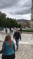Police Officer Points Weapon at Man on Ground During Notre Dame Incident