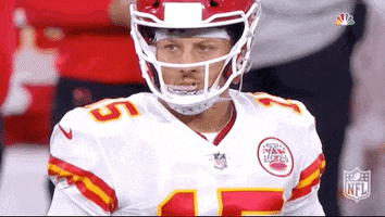 Sports gif. Patrick Mahomes of the Kansas City Chiefs wears his football uniform with his helmet on. He has a serious look on his face as he nods his head and points at someone.  