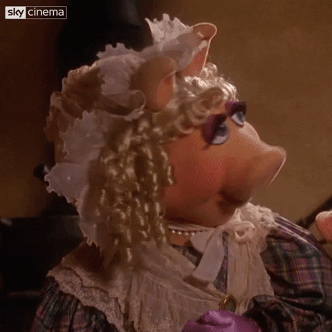 Movie gif. Wearing a Victorian dress and bonnet, Miss Piggy from a Muppet Christmas Carol looks from side to side before speaking to us. Text, "Whatever."