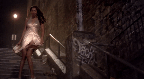 TV gif. Herizen Guardiola as Mylene on The Get Down stands outside on steps. She poses back in forth to show off her golden and glistening dress. 