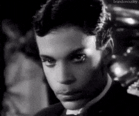 Celebrity gif. Prince is shot in black and white and he gives us his signature deadpan stare into our souls and says, "Boo."