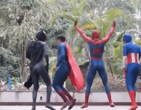 Video gif. Batman, Superman, Spiderman, and Captain America are wearing their skintight superhero costumes and are twerking in broad daylight. They're feeling good and it shows.
