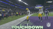 Sports gif. Bo Melton of the Green Bay Packers in the end zone, doing a quick step forward then saluting fans high up in the bleachers, oozing swagger. Text flashes across the screen that reads, "Touchdown."