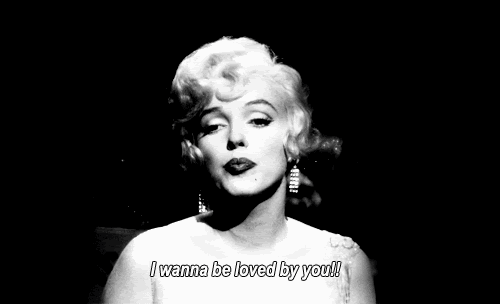 Movie gif. Marilyn Monroe as Sugar in "Some Like it Hot" flicks her wrist and points with a single pinky as she sings seductively to an audience on a darkened stage. Subtitle text reads, "I wanna be loved by you!'