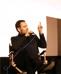 Celebrity gif. Actor Andrew Lincoln sits on a live panel. He raises his arm with his index finger extended as if to point as the word "This" appears above his head.