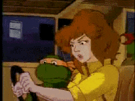 Cartoon gif. Michelangelo from the original Ninja Turtle cartoon is sitting in the passenger seat of a car. He watches the driver struggle with the wheel and looks incredibly frightened.