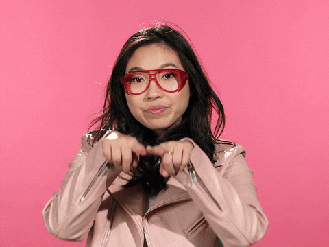 Celebrity gif. Awkwafina smiles as she draws a green heart in the air with her fingers, then pokes it, and it bursts.