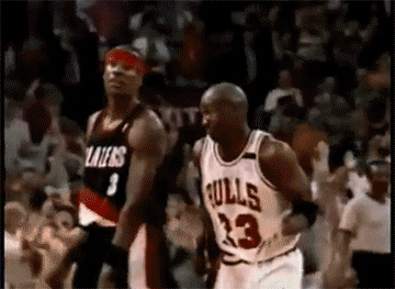 Sports gif. Michael Jordan gives the spectators an amused shrug as he jogs across the court.