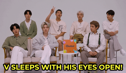 Tonight Show gif. BTS is being interviewed and RM says, "V sleeps with his eyes open!" The camera pans to V and he smiles and says, "Yeah."