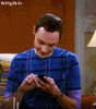 TV gif. Jim Parsons as Sheldon on The Big Bang Theory looks down at his phone as he texts and says, "LOL."