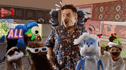 Video gif. A hipster surrounded by chattering puppets in an animated interior space. Text, "ohhhhhh," and "All that we will bring."