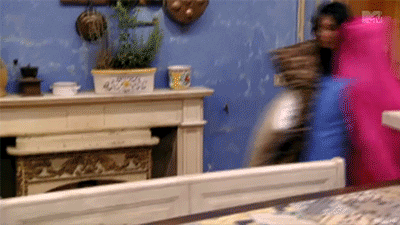 Reality TV gif. Carrying three pillows and a pink satin blanket, Snooki from Jersey Shore runs through a room.