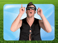 Video gif. Comedian Kyle Gordon, wearing a black vest and shiny goggles pointing upwards with both hands, in a background that looks like a Microsoft home screen.