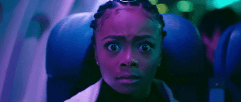 Music video gif. Skai Jackson in Lil Nas X's Panini video has a petrified look on her face, accentuated by ambient purple lighting, and she bolts out of her airplane seat.