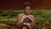 Celebrity gif. Holding a card on the stage at the BET Awards, Taraji P. Henson looks up with a smile and says, “HA!”