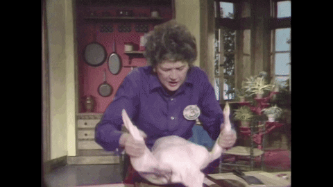 TV gif. Julia Child on her cooking show holds a raw turkey by its legs, bouncing her body up and down as she shakes the turkey, mouth downturned and brow furrowed, struggling through the moment like it's a bit heavy. 