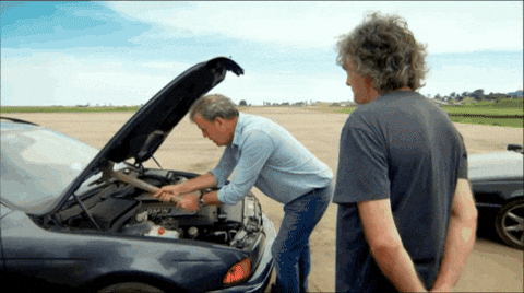 TechDogs-"Prerequisites For Installation Of DeepSeek-R1"-"Man Humorously Fixing Car Engine With a Hammer While Another Watches"