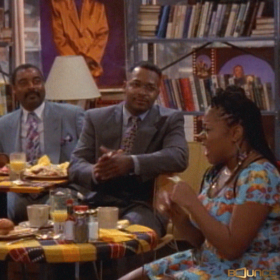 TV gif. Some of the cast from Moesha are seen sitting at tables filled with food, clapping and dancing. They're jubilated about something and are celebrating together. 