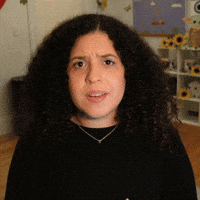 Video gif. A woman raises her eyebrows and smiles as she puts two fingers together to show, “Just a little bit.”