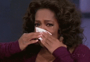 Celebrity gif. Oprah has a tissue to her face and she holds it there to catch her falling tears. She takes a deep breath and looks down at the tissue.