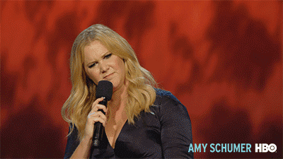 Celebrity gif. Amy Schumer hotels a mic up to her mouth. She looks around with a disgusted look on her face.