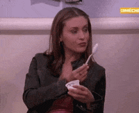 Video gif. With a cup of ice cream, an attractive woman wearing a black denim jacket and a low rise pink tank top purposely drops a plastic spoon and cutely says, "oops" before seductively picking it up, making sure to expose her chest and collarbone.