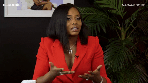 Celebrity gif. Actress Yandy Smith sits in a bright red suit for an interview. She holds her hands up and looks around as if being accused of something. She then shrugs and looks away.