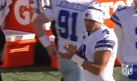 Sports gif. On the sidelines, Dallas Cowboys player Dak Prescott claps his hands together in encouragement.