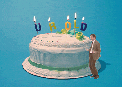 Video gif. Rowan Atkinson as Mr. Bean dances, thrusting his hips, in front of a large white birthday cake. On top of the birthday cake are candles that spell out “Your Old.”
