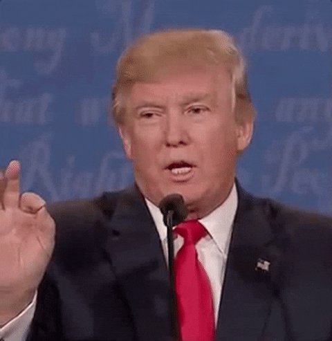 Politics gif. Donald Trump behind a mic, raises his index finger and opens his mouth, about to speak, then drops his hand and closes his mouth.