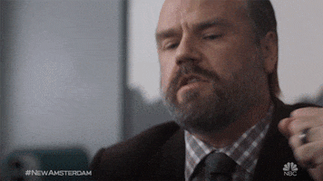 TV gif. Seated in an office, Tyler Labine as Dr. Iggy Frome in New Amsterdam angrily slams his hands on the armrests of his chair before bringing his hand to his face, covering his eyes exhaustedly.