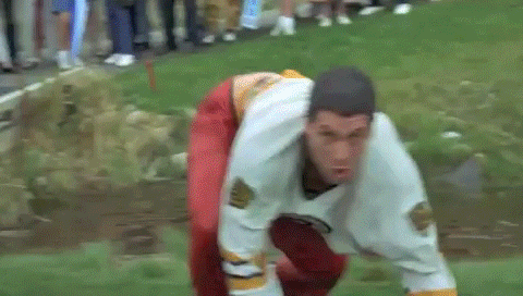 Movie gif. Adam Sandler as Happy Gilmore tackles Bob Barker before they roll down a hill together.