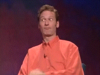 Reality TV gif. Ryan Stiles on Whose Line Is It Anyway sits on stage and makes his fingers into a circle and thrusts a finger through the circle towards Drew Carey. Drew looks back at him smiling and then makes a blowjob gesture with a thrusting fist and his tongue on his cheek.