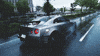 Video gif. Silver Nissan GT-R sports car speeding down a wet street.