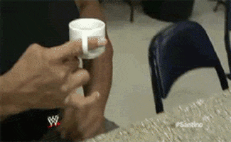 Sports gif. A bulky pro wrestler backstage drinking from a teacup that he wears like a ring on his finger.