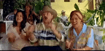 Movie gif. Jessica Mas as Maya, Enoc Leano as Arbitro and Dolores Heredia as Elvira clap and cheer at a bench while watching a soccer game.