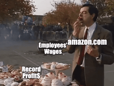 TV gif. Mr. Bean stands happily in front of a table of desserts, stuffing his face with a cupcake and not noticing a giant military tank rolling by and completely destroying his car. Mr. Bean is labeled "Amazon dot com," the dessert table is labeled "record profits," the tank is labeled "inflation," and the car is labeled "employees' wages."