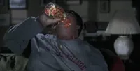 Movie gif. Eddie Murphy as Sherman Klump in The Nutty professor pours a whole jar of jelly beans into his mouth like he’s trying to drown himself in it. The jelly beans spill out of his mouth and roll down his chest and onto the ground.