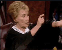 Reality TV gif. Judge Judy taps on her watch and bangs on her desk emphasizing the need to hurry up and not waste her time.