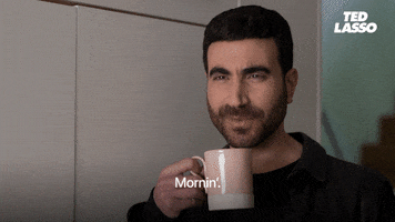 TV gif. Brett Goldstein as Roy on Ted Lasso holds a coffee mug and nods as he says "mornin'," which appears as text.