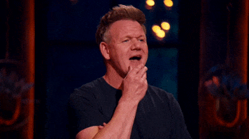 Reality TV gif. Gordon Ramsay on Next Level Chef opens his mouth to say something, but stops and places a finger on his mouth. He then turns to look at someone as if they have an answer.