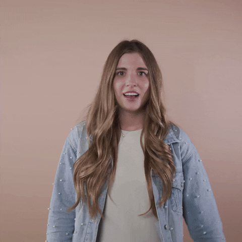 Reaction gif. A light-skinned woman with big eyes, shiny bronde hair, and cerebral palsy throws a hand to her heart with a cringe, saying, "Yikes!"