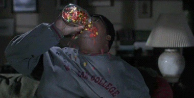 Movie gif. Eddie Murphy as Sherman Klump in The Nutty professor pours a whole jar of jelly beans into his mouth like he’s trying to drown himself in it. The jelly beans spill out of his mouth and roll down his chest and onto the ground.
