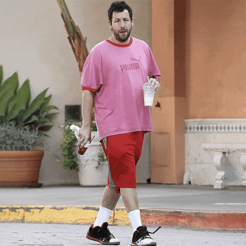 Text gif. Smiley face sticker rolls in, closely followed by another that says "Shabbat fit," then a Hamsa, then another sticker with a smiley face that bears the message "Shabbat shalom," over a man-on-the-street photo of an unshaven Adam Sandler wearing an oversized pink t-shirt and his signature basketball shorts.